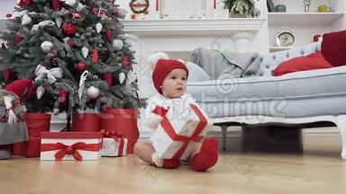 一个穿着圣诞衣服的可爱的小<strong>宝宝</strong>坐在地板上，拿着礼物在附近的圣诞<strong>照片</strong>